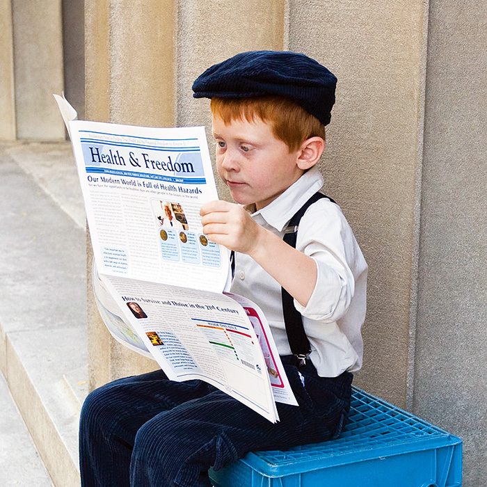 A little boy reading the newspaper