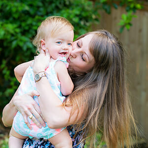 A woman kissing her toddler on the cheek