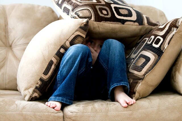 Little boy hides in the couch, because he fears the dentist.