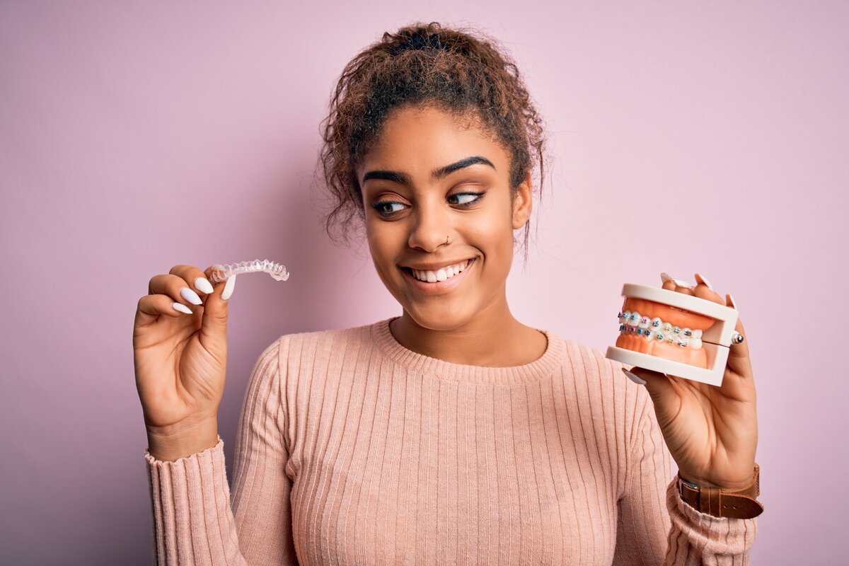 Woman comparing clear aligners to traditional metal braces for orthodontic treatment at Randall K. McVey, DMD PA in Garden City, KS Woman comparing clear aligners to traditional metal braces for orthodontic treatment at Randall K. McVey, DMD PA in Garden City, KS