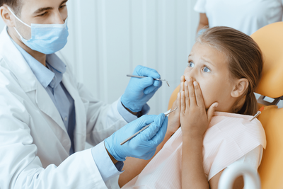 Conscious Sedation Dentistry Garden City Girl showing fear while sitting in dental chair before sedation dentistry
