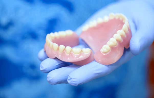 Full Dentures Garden City KS Dentist holding custom full dentures at Randall K. McVey, DMD PA in Garden City, KS