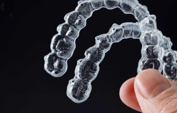 SimplyClear Clear Aligners Garden City KS Person holding up clear aligners for discreet teeth straightening at Randall K. McVey, DMD PA in Garden City, KS